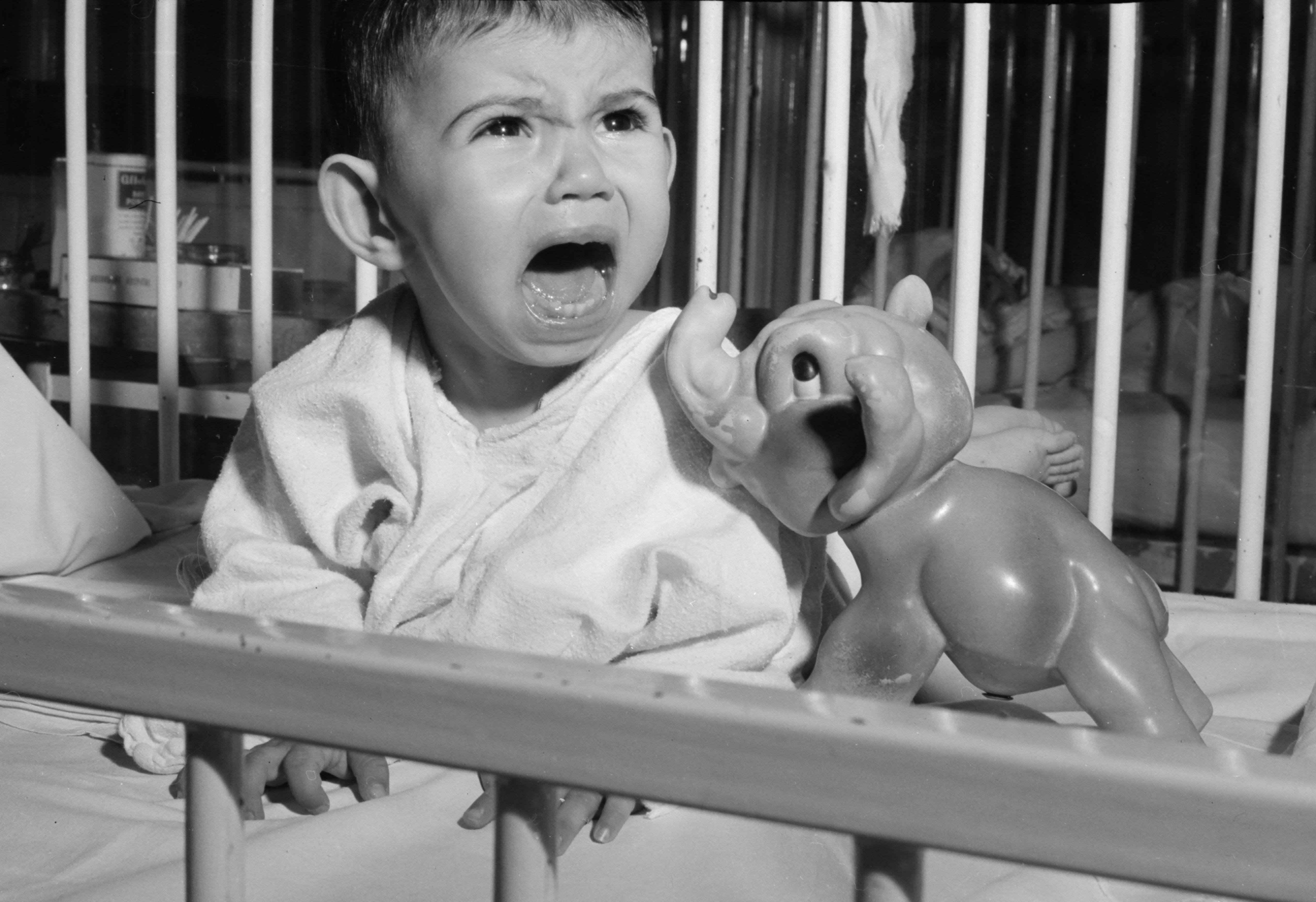 A very unhappy toddler screams in his crib.