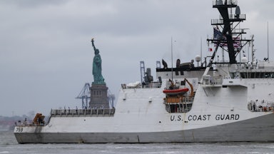 U.S. Coast Guard ship sails near the Statue of Liberty.