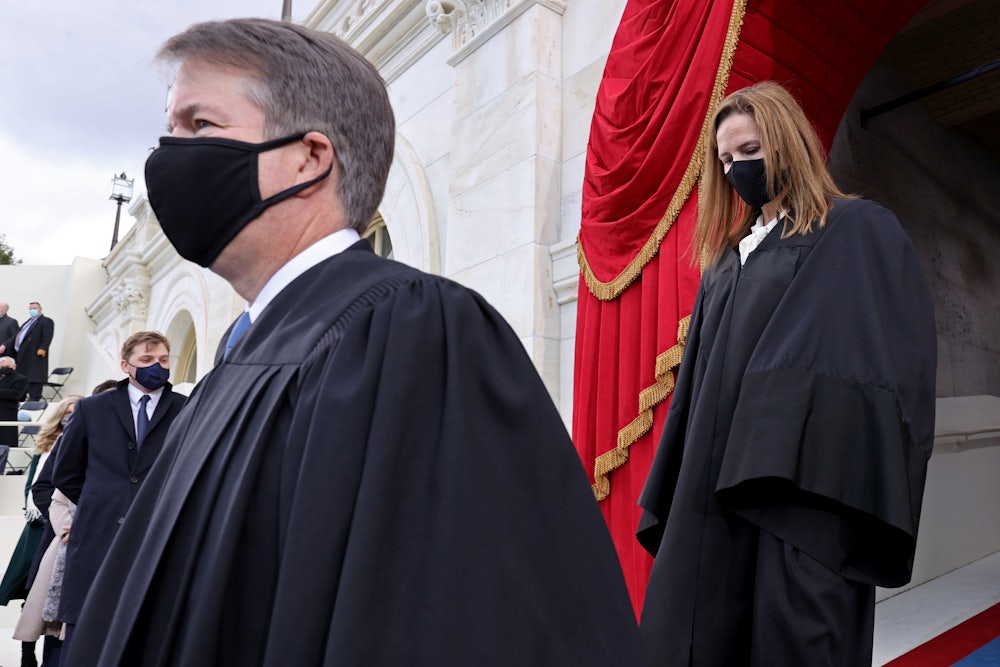 A masked Brett Kavanaugh is trailed by a masked Amy Coney Barrett as the two Justices make their way to their seats.