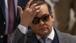 Former Representative George Santos touches his forehead while walking