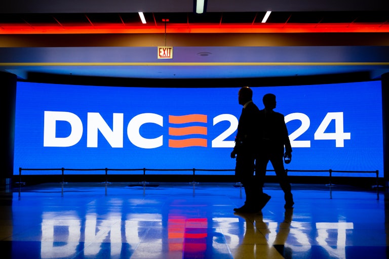Silhouettes of two men standing in front of a sign that reads DNC 2024.