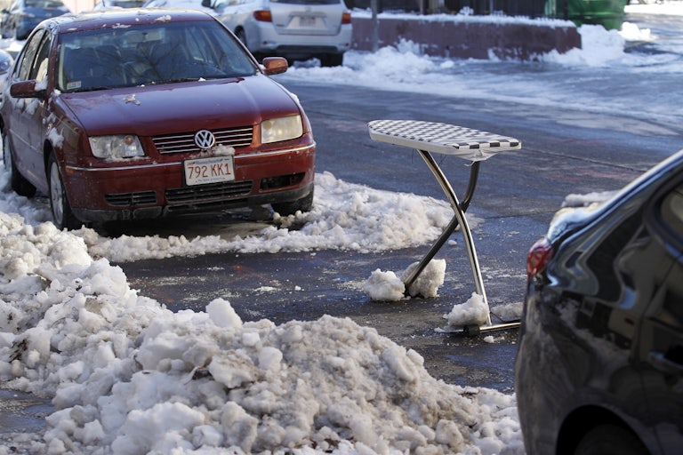 An ironing board is used as a space saver to claim a shoveled parking spot on East 4th Street in South Boston