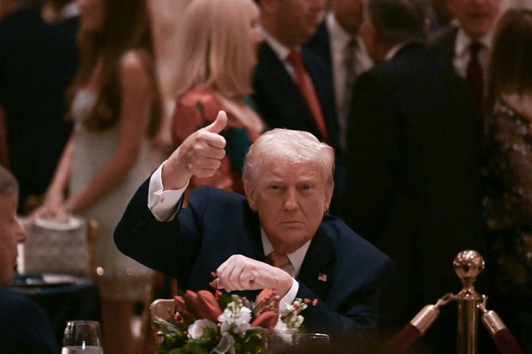 Donald Trump holds a thumbs up for the camera while seated at a table at Mar-a-Lago.