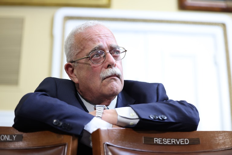 Representative Gerry Connolly crosses his arms on the back of two chairs.