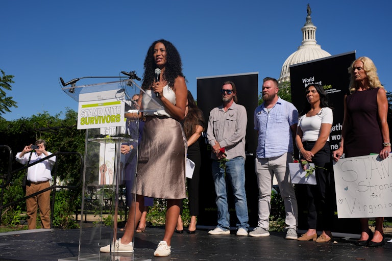 Epstein survivor victims stand on a stage in front of the U.S. Capitol.
