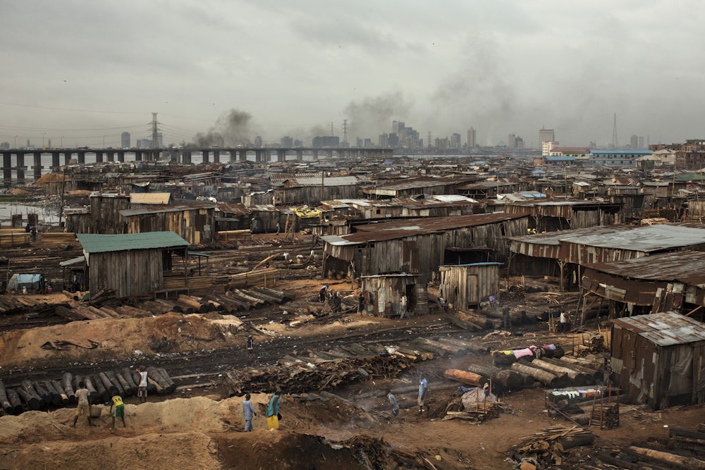 Smoke billows from logs covered with soil next to sheds in Lagos.