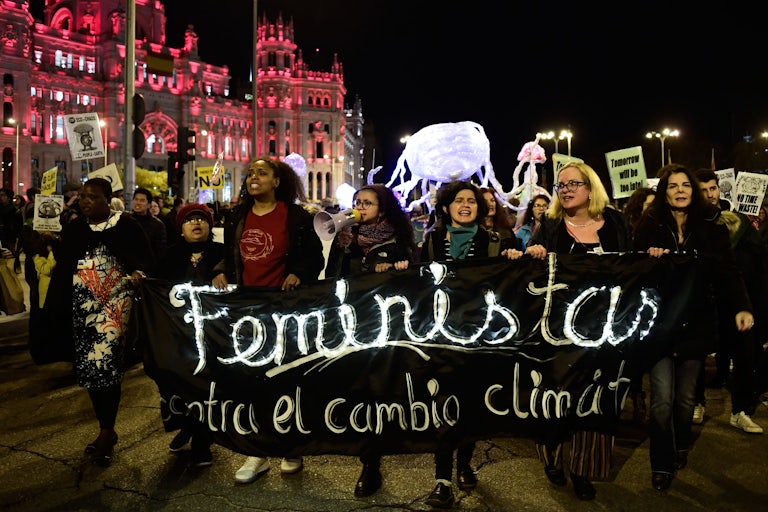 Activists walk holding a banner.