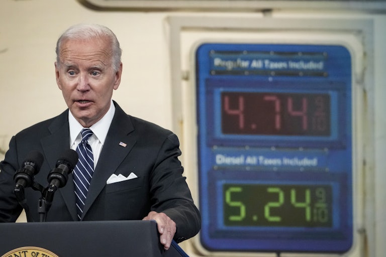 Biden speaks in front of a sign displaying gas prices.
