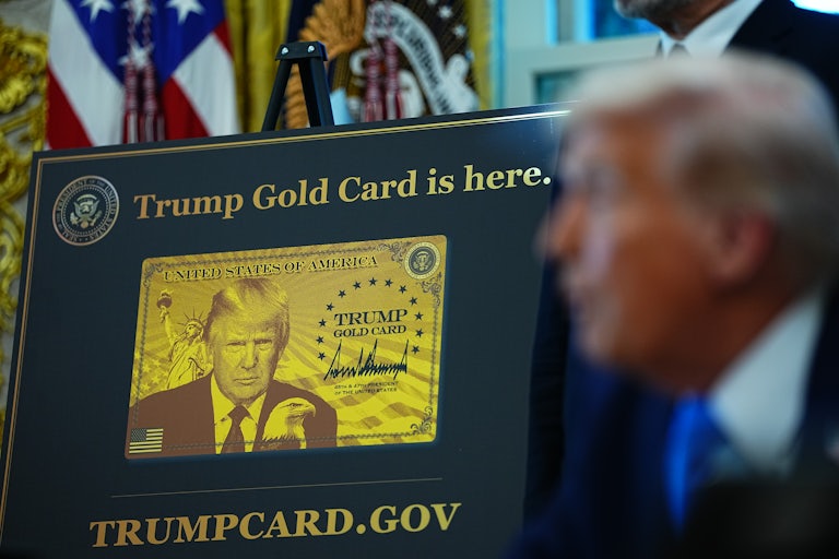 Trump stands in front of a gold image of the "Trump card"