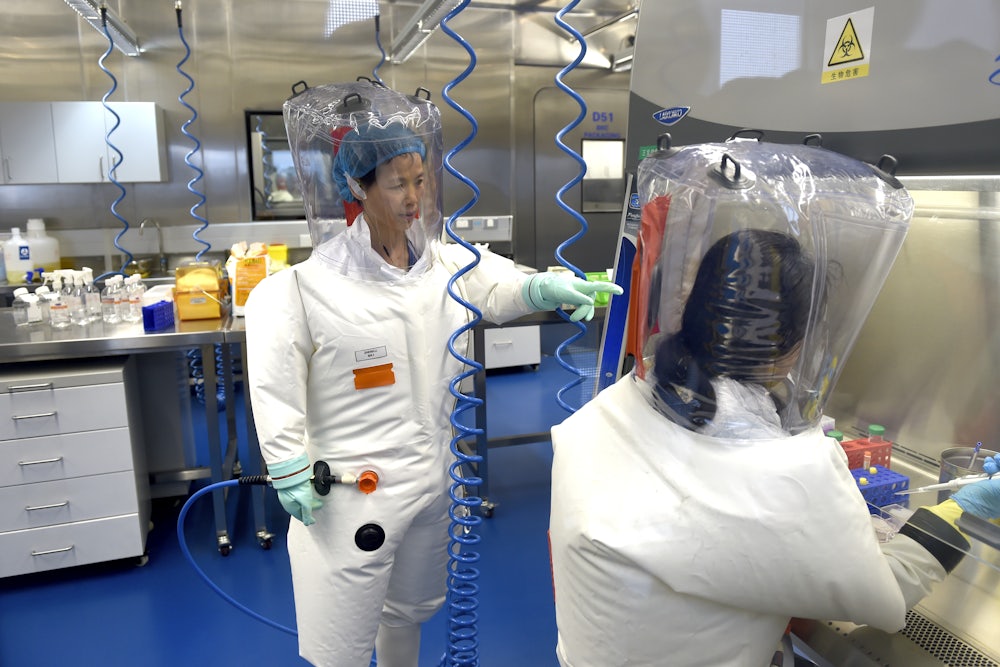 Two researchers in protective gear work in a lab.