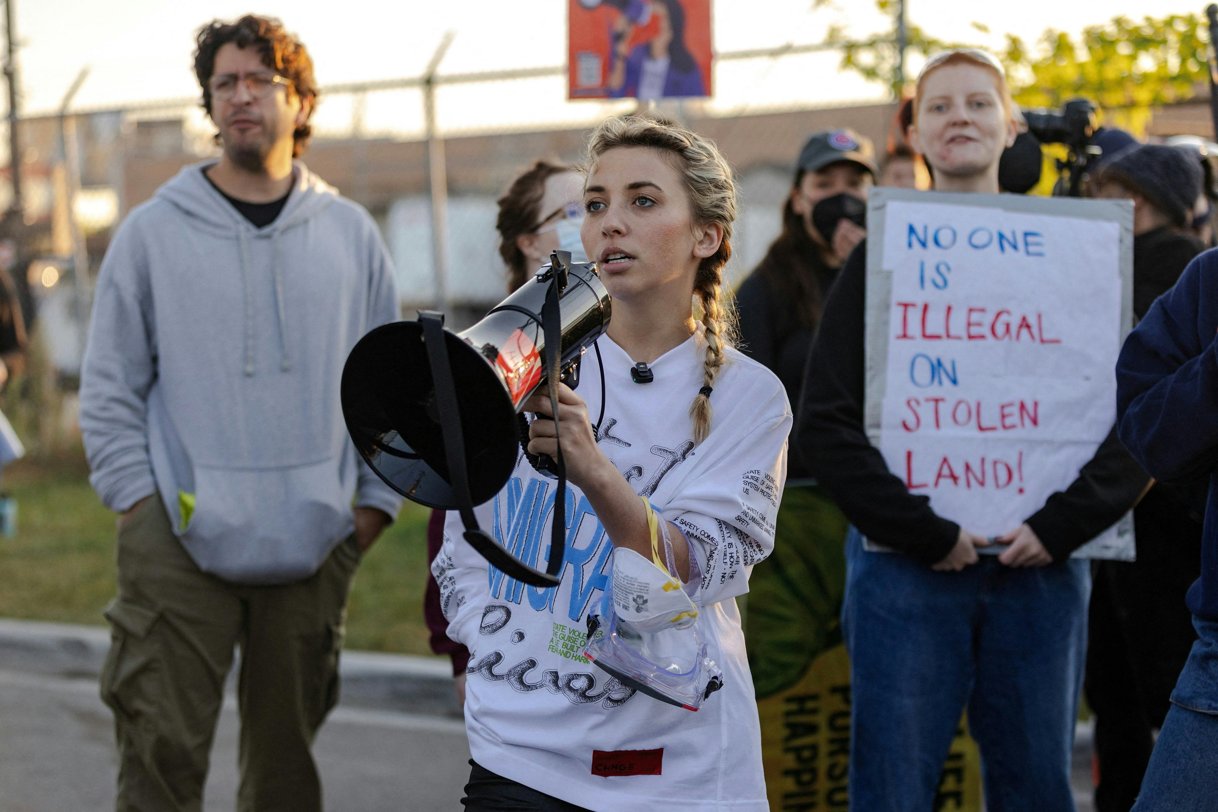 Democratic congressional candidate Kat Abughazaleh holds a megaphone outside of the Broadview ICE processing facility with other protestors visible behind her.