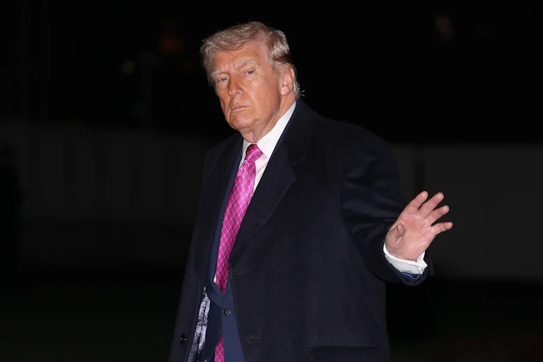 Donald Trump waves while walking outside the White House