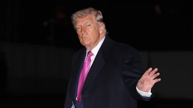 Donald Trump waves while walking outside the White House