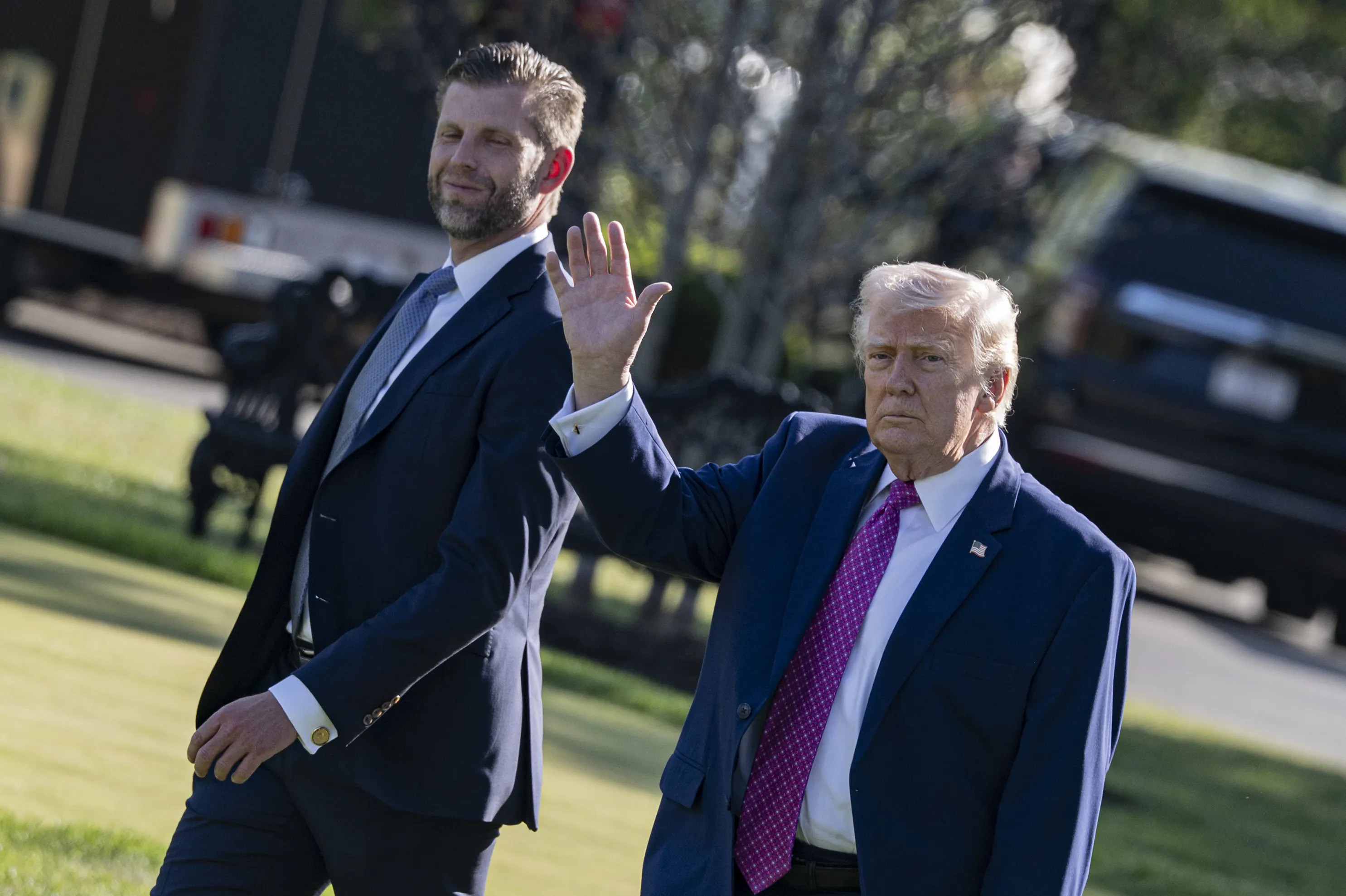Donald Trump waves while walking next to his son Eric Trump outside the White House