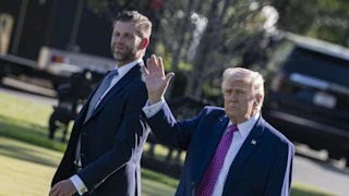 Donald Trump waves while walking next to his son Eric Trump outside the White House