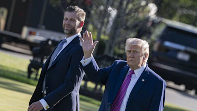 Donald Trump waves while walking next to his son Eric Trump outside the White House