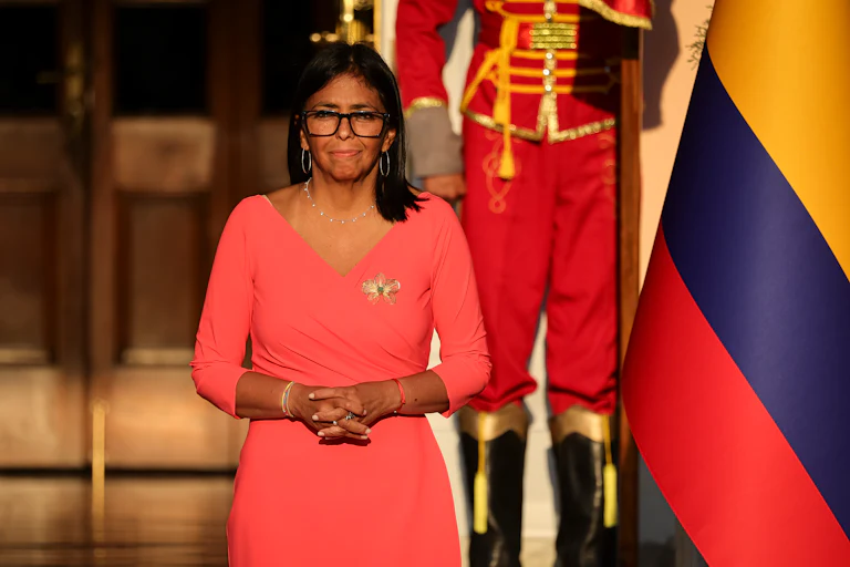 Acting Venezuelan President Delcy Rodriguez stands with her hands folded in front of her stomach outside the presidential residence