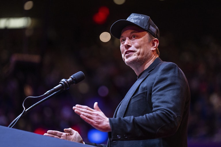 Elon Musk gestures while standing at a podium
