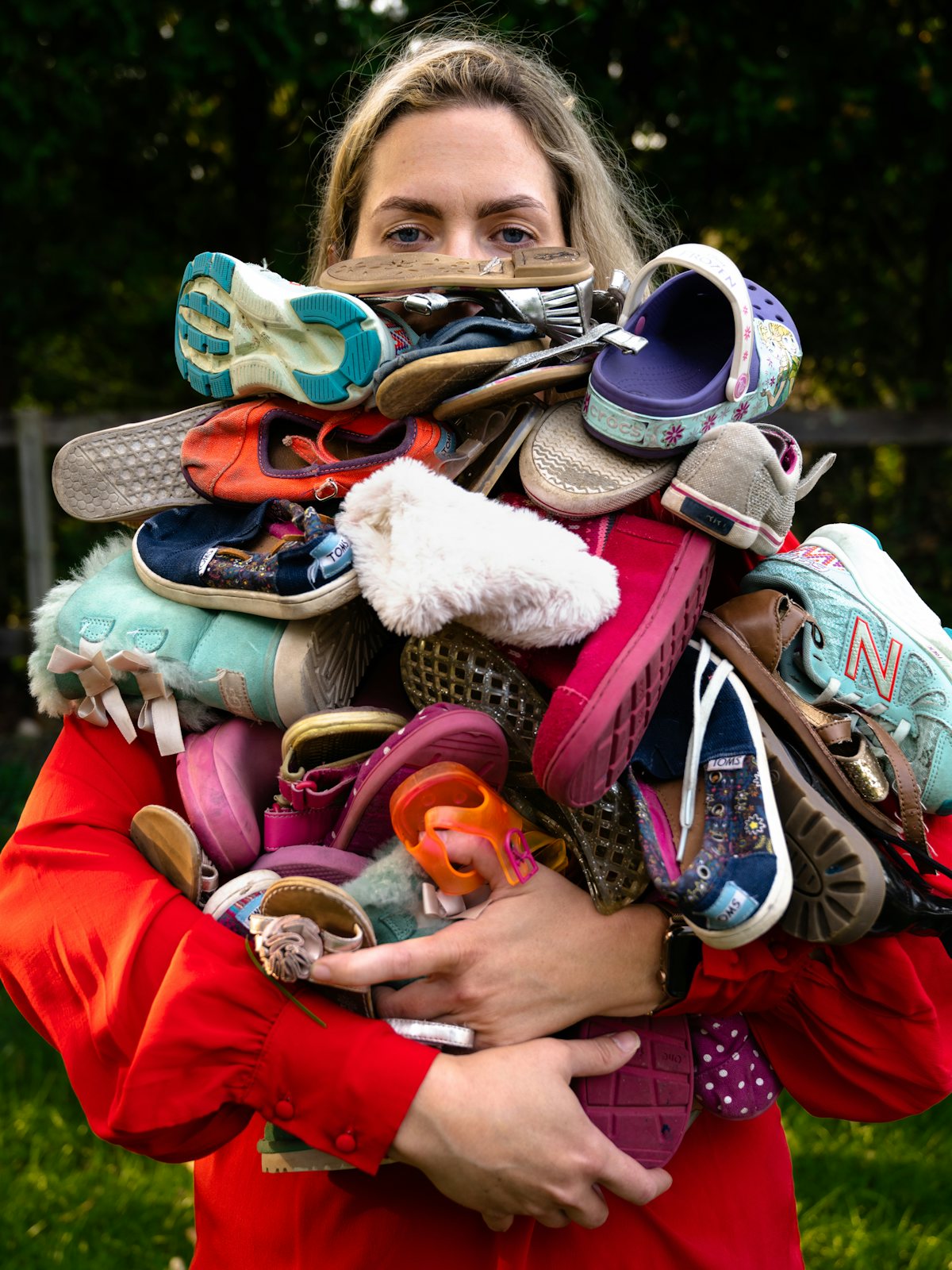 A tired mom carries a huge pile of laundry that almost covers her face. The title is Optimizes Efficiency from the series “Résumé of a Stay at Home Mom” by