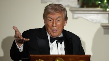 Donald Trump speaks at a lectern while stretching out a hand for emphasis.