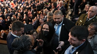 Aliya Rahman, wearing a face mask, is surrounded by people trying to escort her out of Trump's State of the Union.