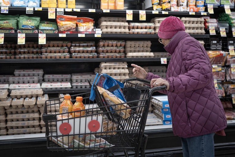 A shopper looks at the price of eggs in a grocery store.