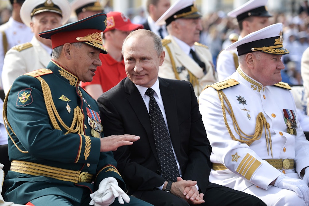 President Putin sits, smiling, between Russia's defence minister and the commander in chief of the Russian Navy, in 2017.