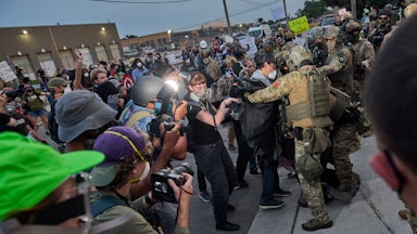Federal agents violently confront protesters as reporters capture the scene.