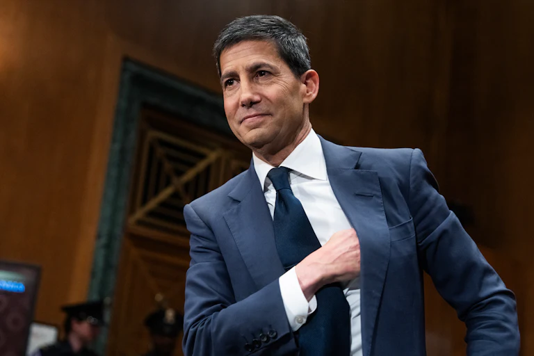 Kevin Warsh stands with his hand inside his jacket ahead of a Senate committee hearing