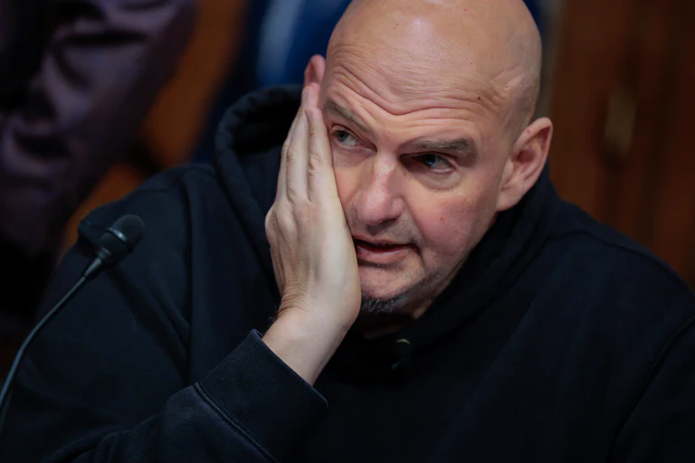 Senator John Fetterman puts his hand on his face and looks to the side