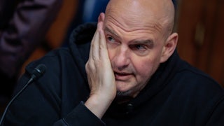 Senator John Fetterman puts his hand on his face and looks to the side