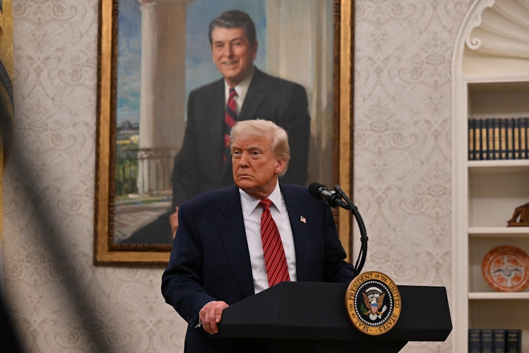 Donald Trump looks to the side as he stands at a podium in the Oval Office