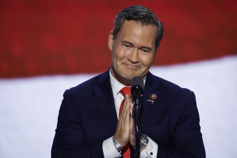 Mike Waltz clasps his hands together in front of a microphone.
