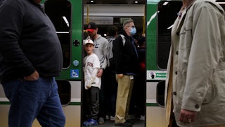 Passengers both masked and unmasked board a Green Line train.