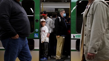 Passengers both masked and unmasked board a Green Line train.