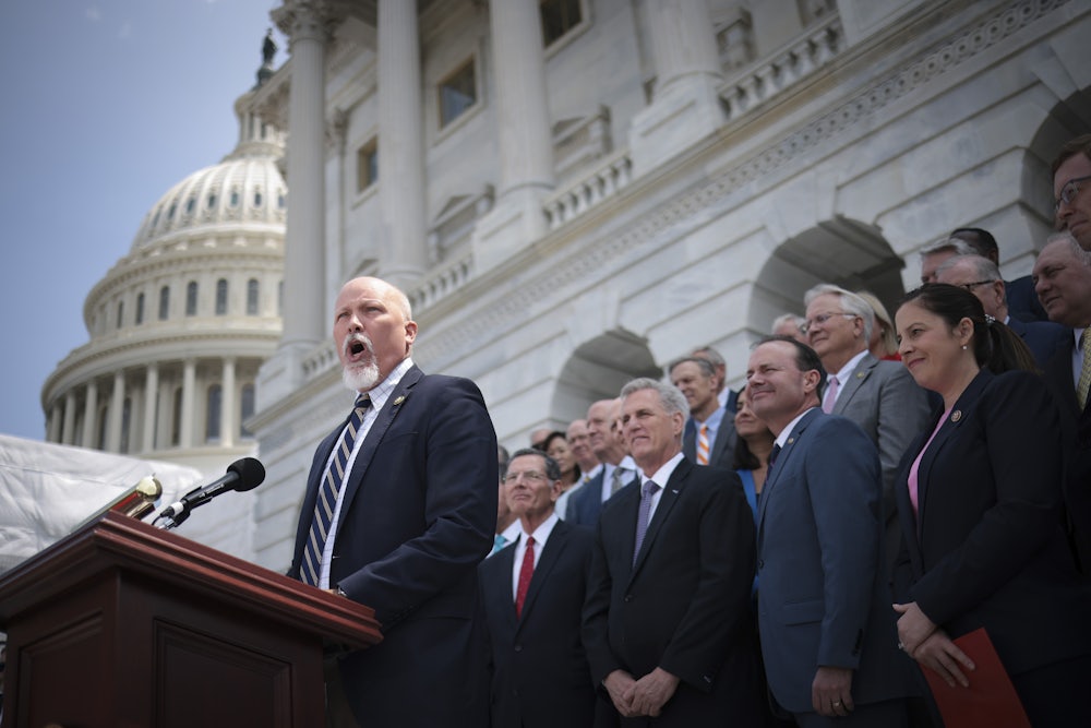 Chip Roy speaks at a lectern with other legislators standing behind him.