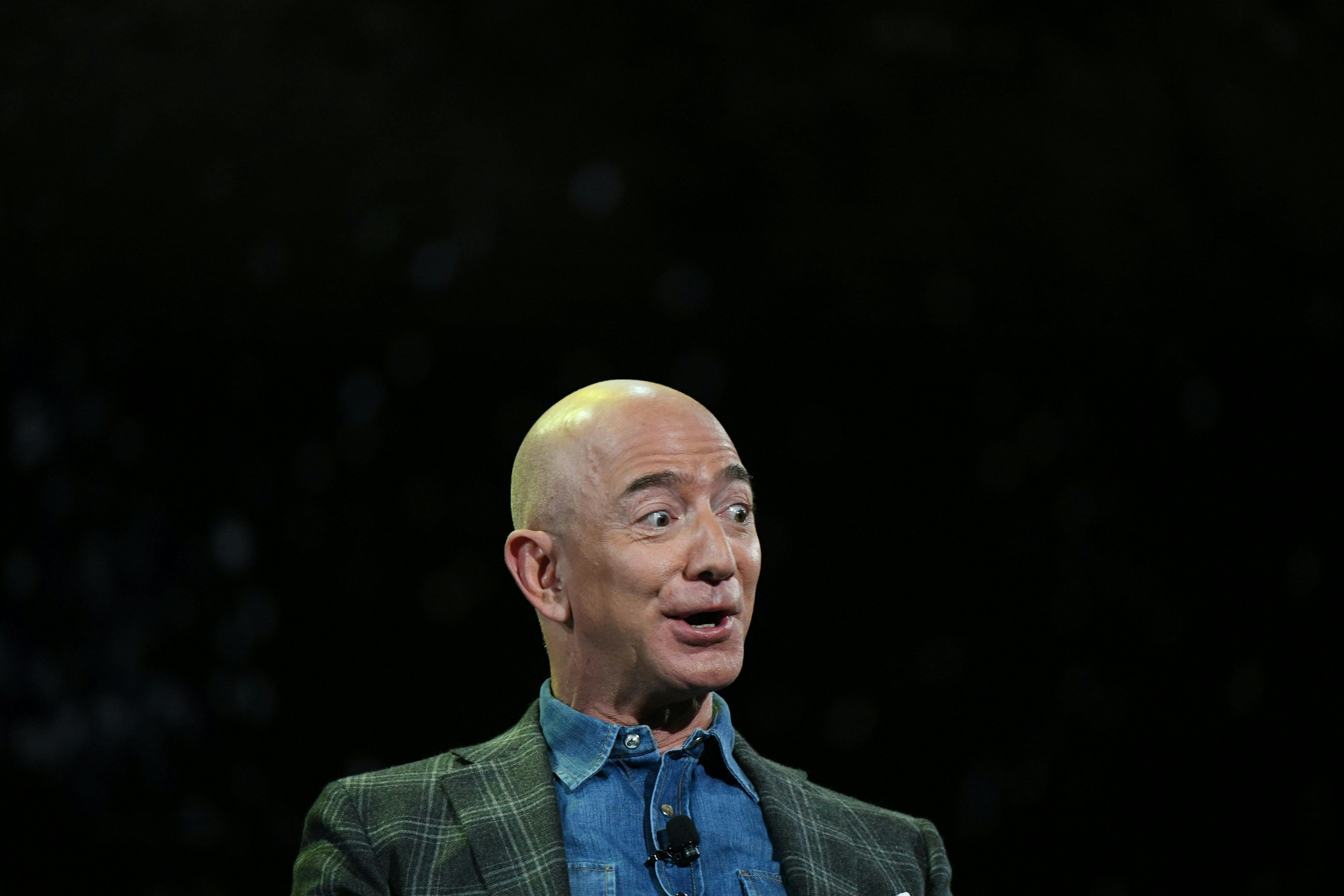 Jeff Bezos, against a black backdrop, looks surprised and excited 