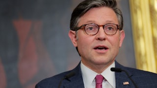 House Speaker Mike Johnson looks shocked while speaking at a lectern.