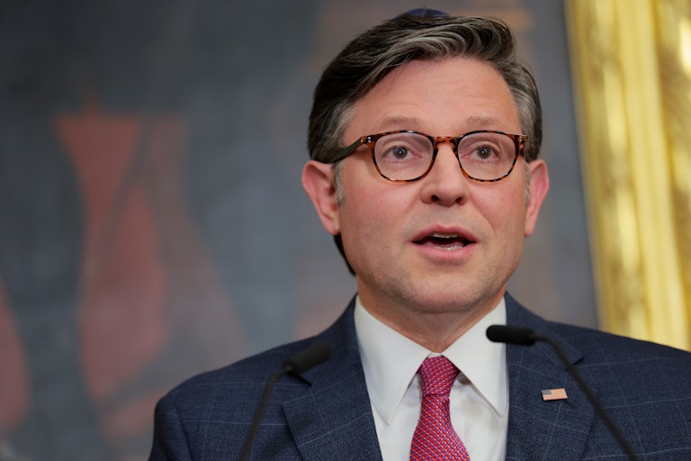 House Speaker Mike Johnson looks shocked while speaking at a lectern.