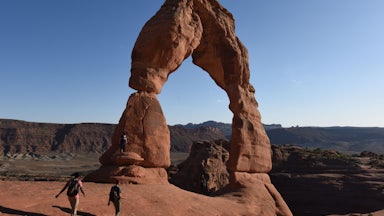 People walk toward a natural rock formation.