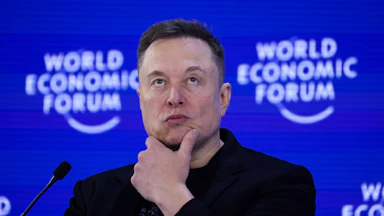 Elon Musk holds a hand on his chin