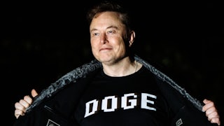 Elon Musk stands outside the White House and holds open his jacket to reveal the word "DOGE" printed on his shirt