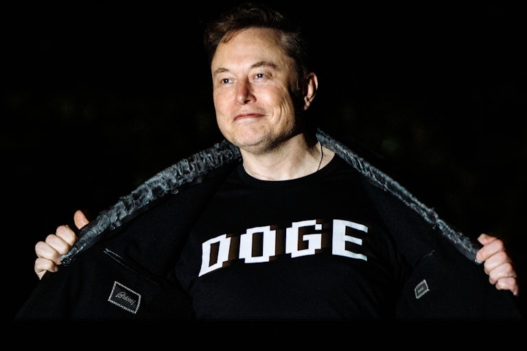 Elon Musk stands outside the White House and holds open his jacket to reveal the word "DOGE" printed on his shirt