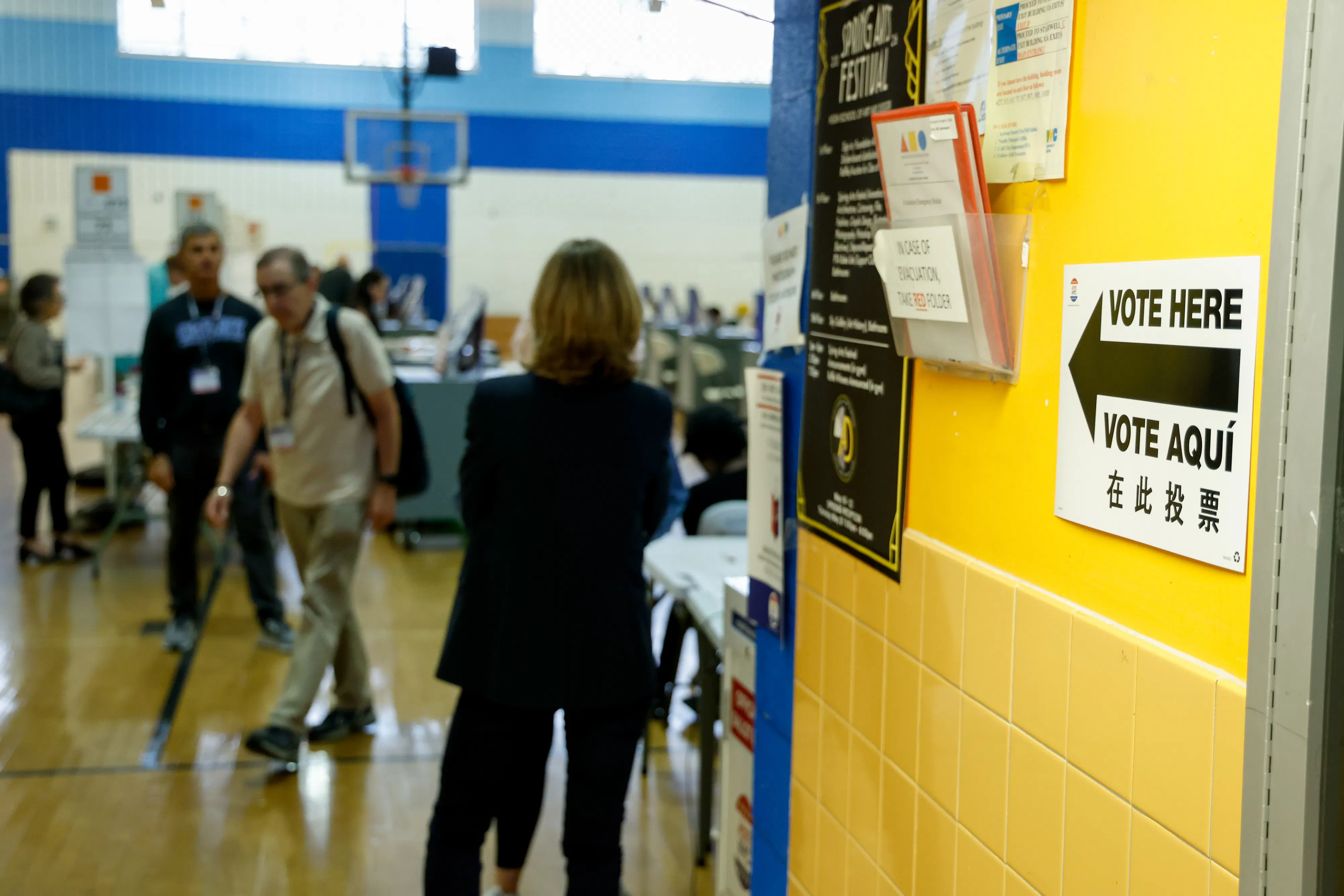"Vote Here” signage and voters at a polling location