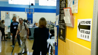 "Vote Here” signage and voters at a polling location