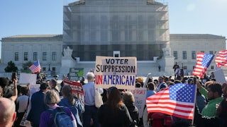 Protesters hold up U.S. flags and a sign that reads "Voter Suppression is Unamerican" while standing in front of the Supreme Court.