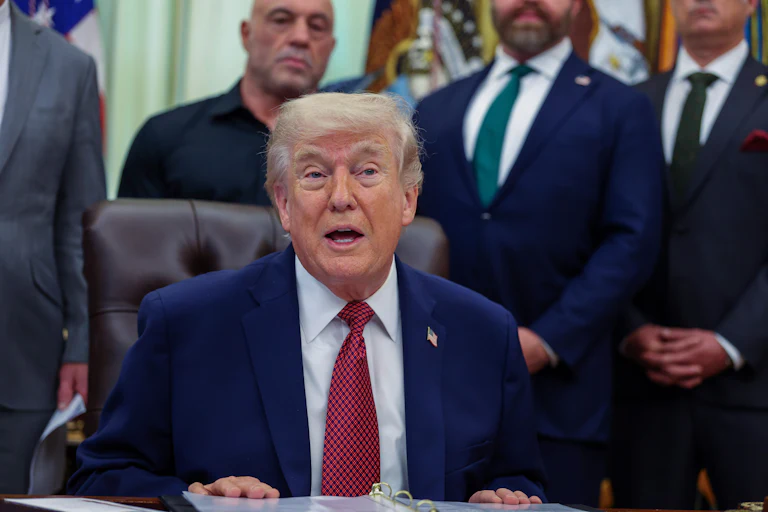 Donald Trump speaking behind his desk in the Oval Office of the White House