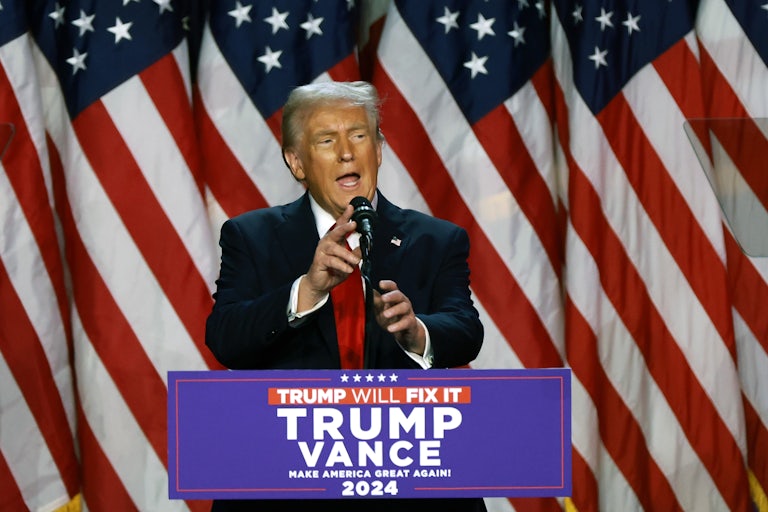 Donald Trump touches the microphone on a podium while speaking