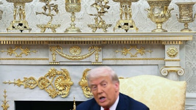 Gold colored ornaments and decor are seen as President Donald Trump speaks during a meeting in the Oval Office.