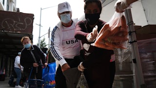 A masked couple collects carrots at a food bank.